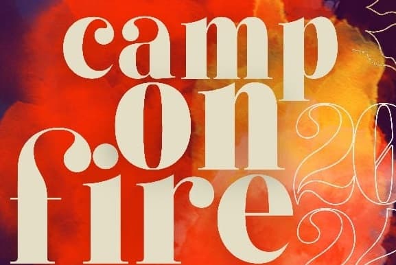 Parte de uma logo, com uma fumaça alaranjada e amarelada no fundo e os dizeres Camp on Fire na frente