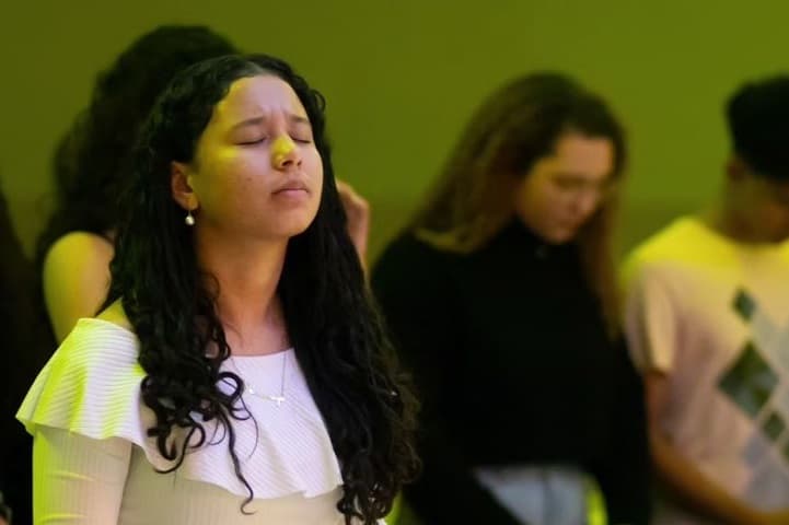 Foto de alguns jovens em uma igreja de olhos fechados