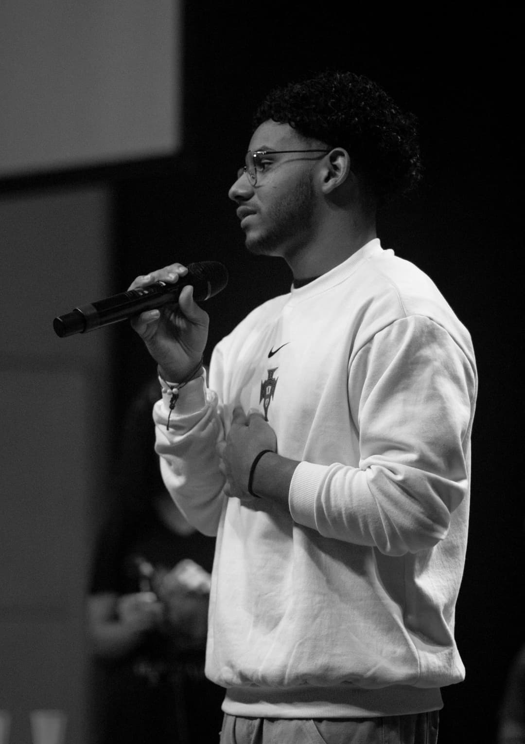 Foto em preto e branco de um jovem segurando um microfone em uma igreja